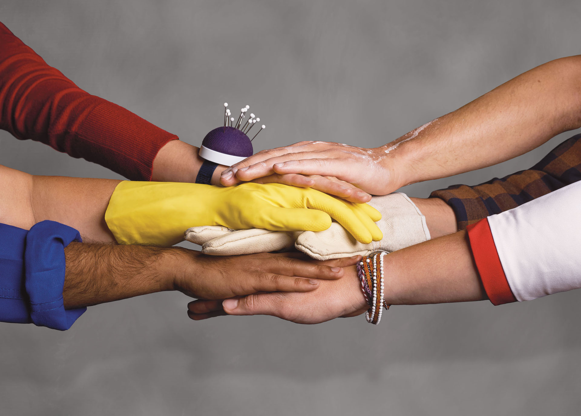 Verschiedene Hände übereinander und Würfel mit weißer Schrift "Stark. Sozial. Vor Ort.".