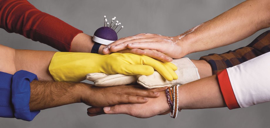Verschiedene Hände übereinander und Würfel mit weißer Schrift "Stark. Sozial. Vor Ort.".