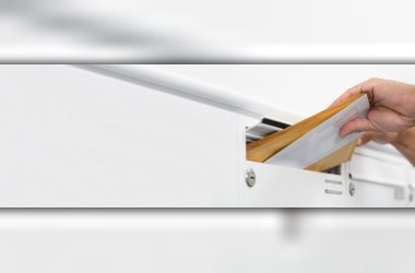 Brief wird in den Schlitz eines weißen Briefkastens geschoben.