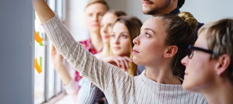 Mehrere Menschen stehen vor einer Präsentationswand.