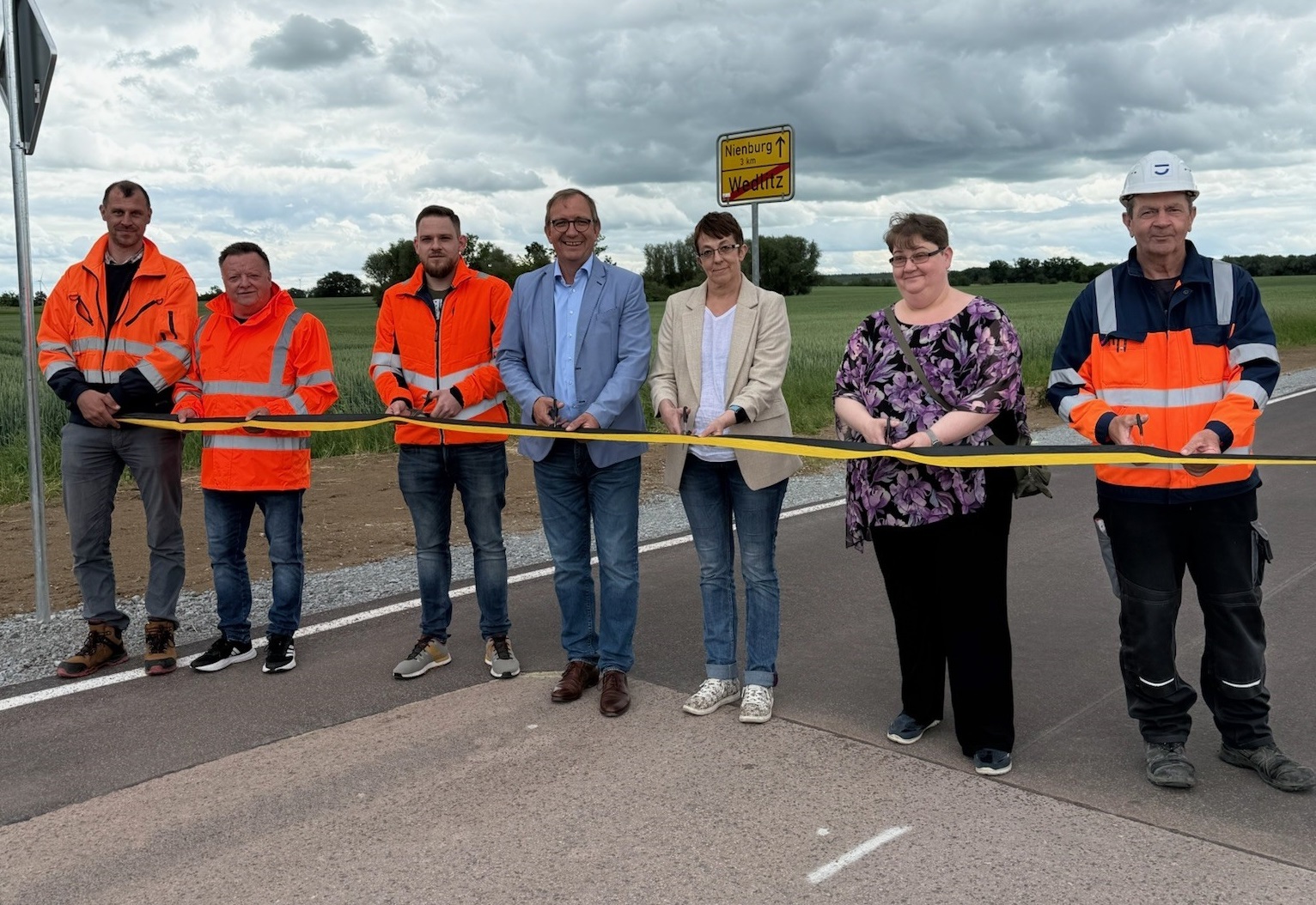 District Administrator Markus Bauer (4th from left) and Nienburg's Mayor Susann Falke (5th from left) at the official opening of the district road 2101 near Wedlitz. Other people involved in the renovation can also be seen.