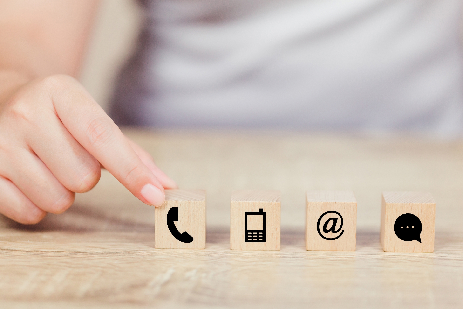 Hand und 4 Würfel mit Symbolen zum Thema Kontakt.