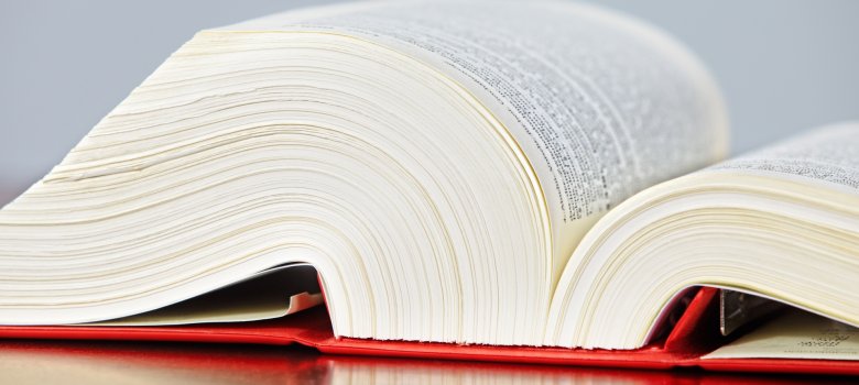 Aufgeschlagenes Gesetzbuch mit rotem Einband.