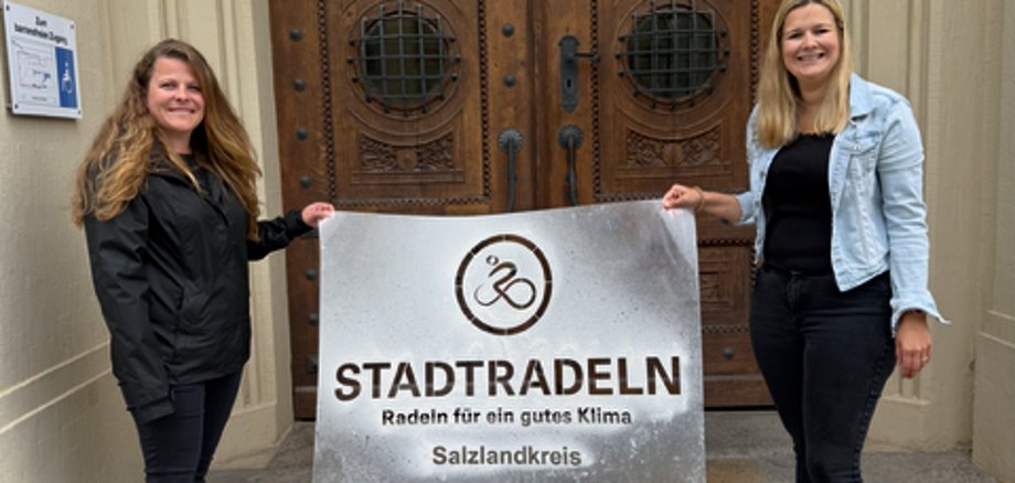 Kati Steinhausen (izquierda) y Luisa Brune, del distrito de Salzlandkreis, han colocado el logotipo frente a la sede de la administración del distrito en Bernburg.