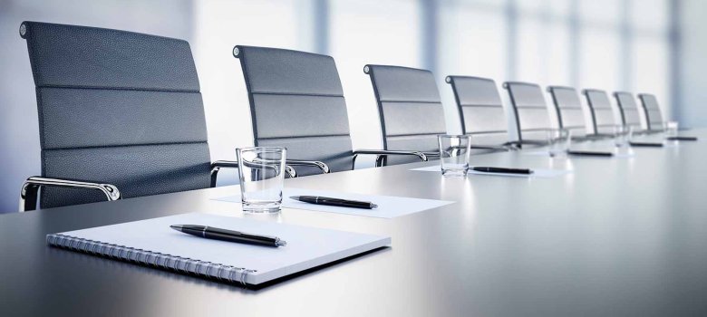 Beratungstisch mit Stühlen. Auf dem Tisch befindet sich an jedem Platz Block mit Stift.