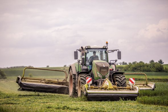 Tracteur équipé d'une combinaison de faucheuses lors de la fauche de l'herbe Tracteur équipé d'une combinaison de faucheuses lors de la fauche de l'herbe