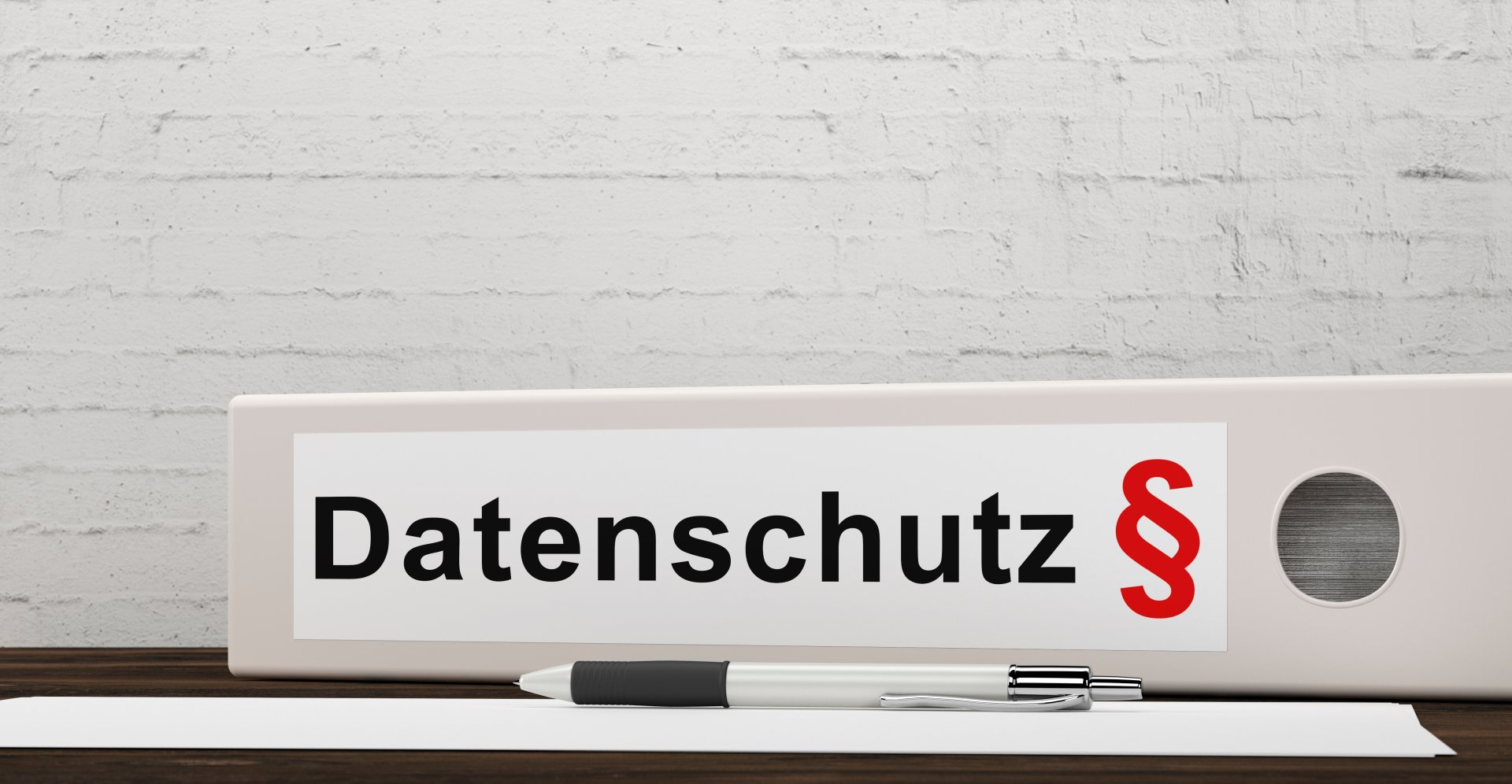 Datenschutz Weißer Ordner mit schwarzer Aufschrift "Datenschutz" und rotem Paragrafenzeichen auf dem Rücken.