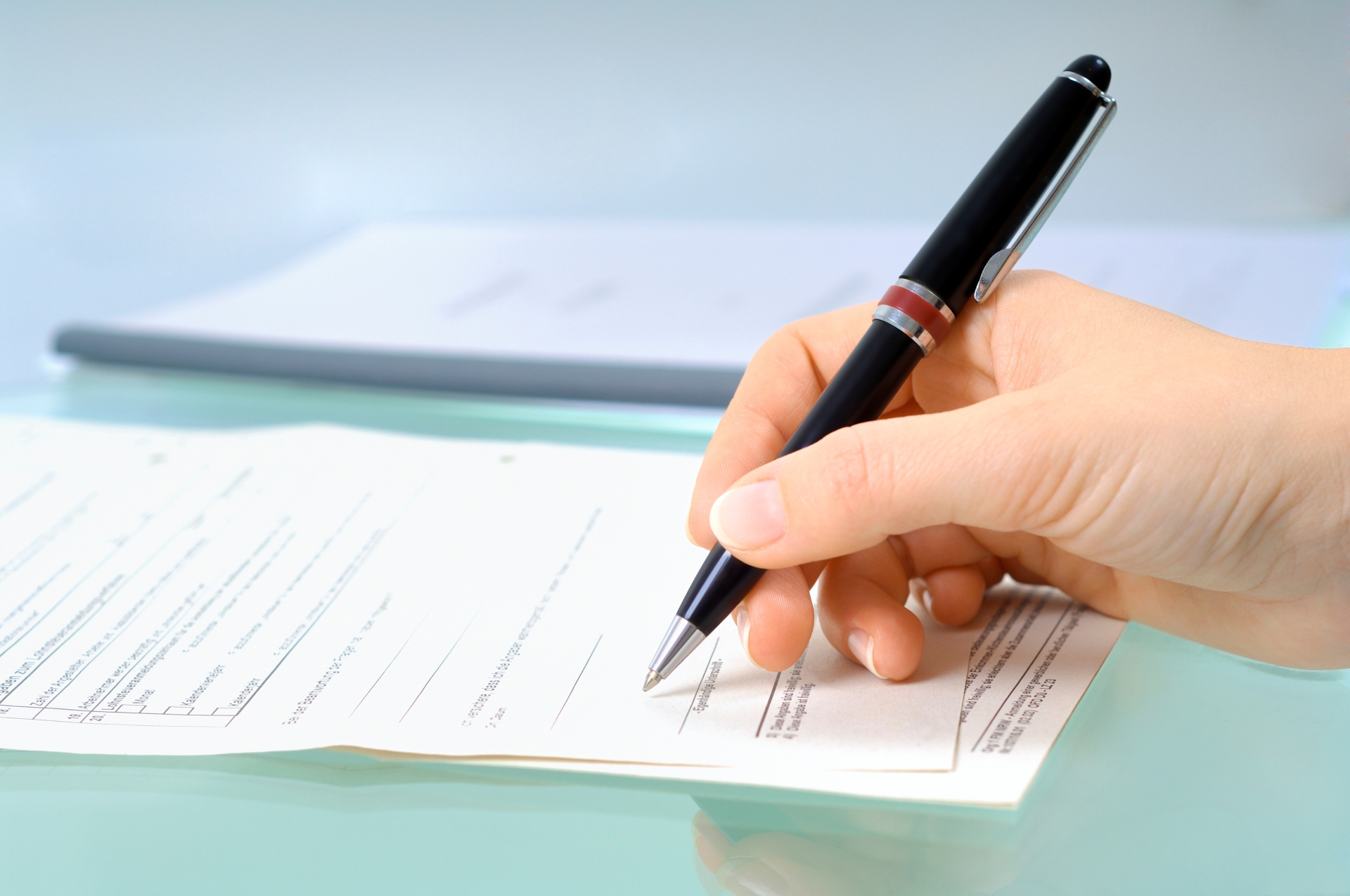 Unterschrift Hand mit schwarzem Stift unterschreibt ein Formular.