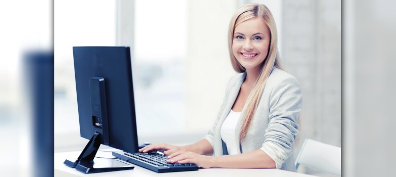 Frau bei der Büroarbeit vor Bildschirm und Tastatur sitzend.